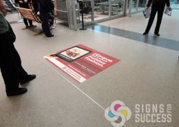 This ad gets walked on thousands of times daily and still looks great, with custom floor decals by Signs for Success at Spokane Airport, ads for Riverpark Square