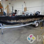 this non-repeating camouflage wrap was printed and cut out then applied just above water line for a unique camo wrap on this black boat in Spokane, camo vinyl boat wrap