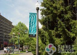 Riverfront Park welcome pole banner on post by signs for Success, with changeable sponsor decals