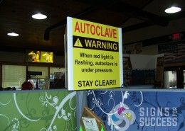 This hanging sign for autoclave is three sided and hangs from the ceiling in manufacturing facility to show warning sign, dimensional hanging signs spokane